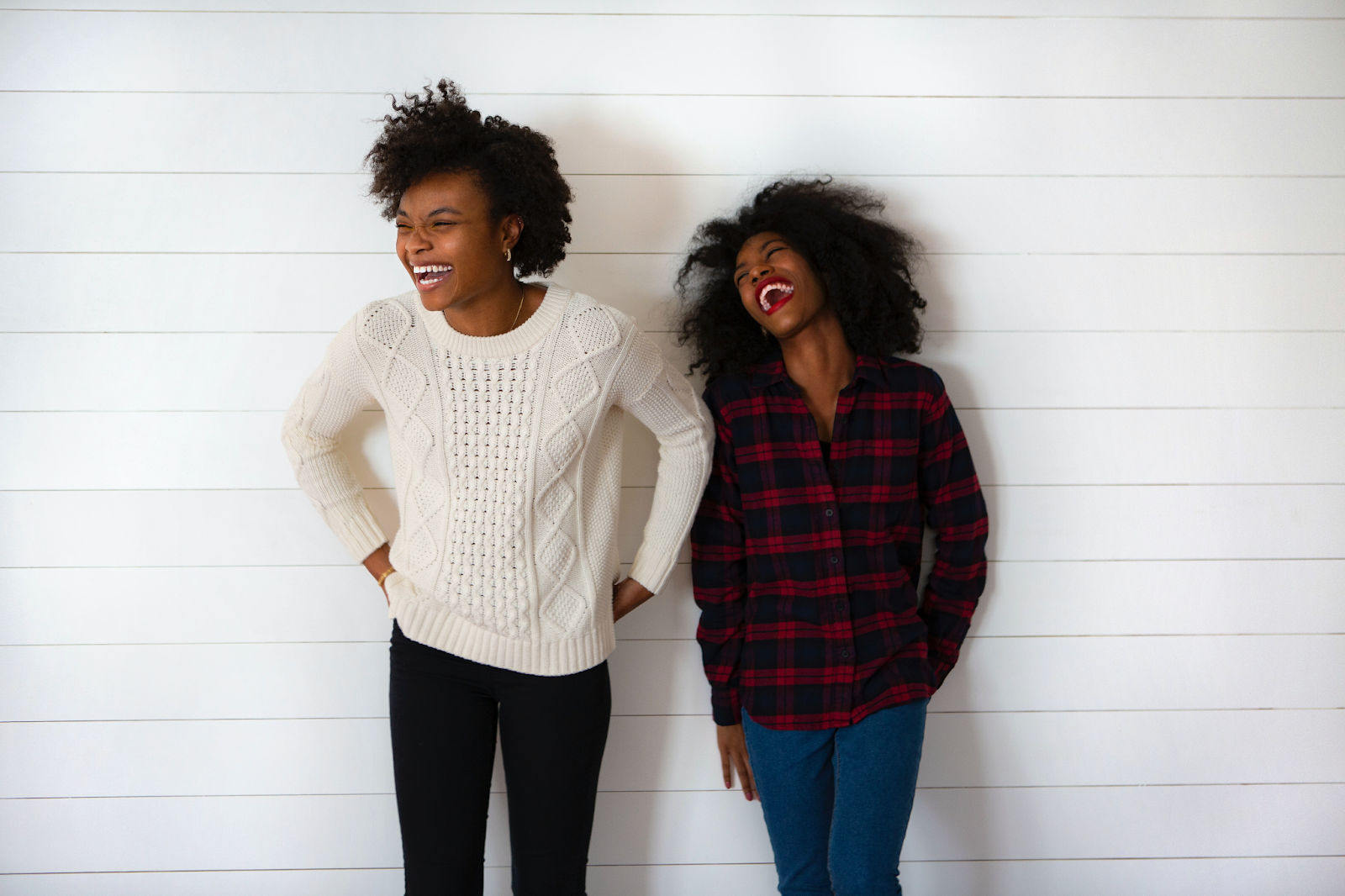 Two young Black people with natural hair laughing widely.