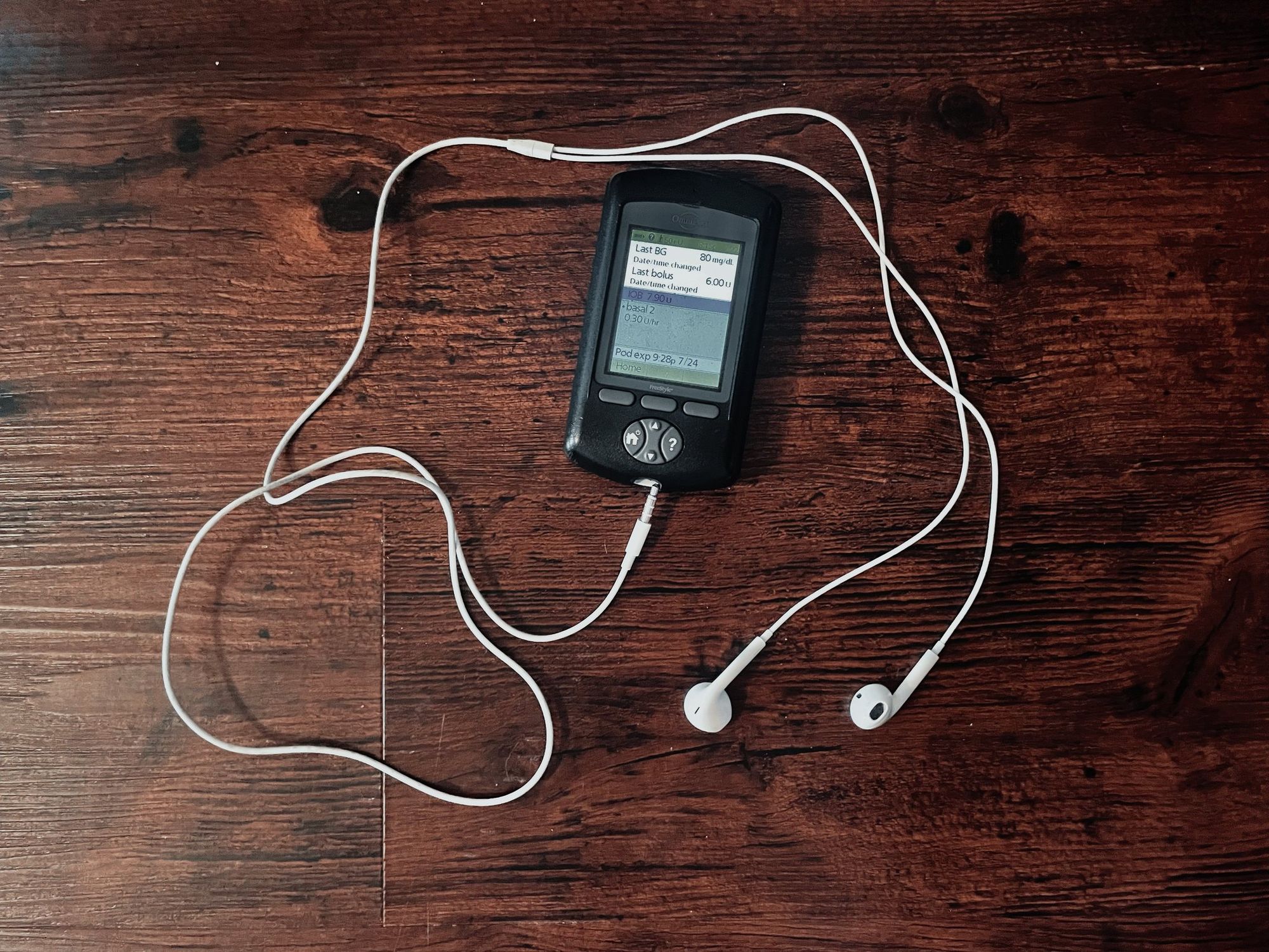 Earbuds curled around a personal diabetes manager showing the last measurement taken.